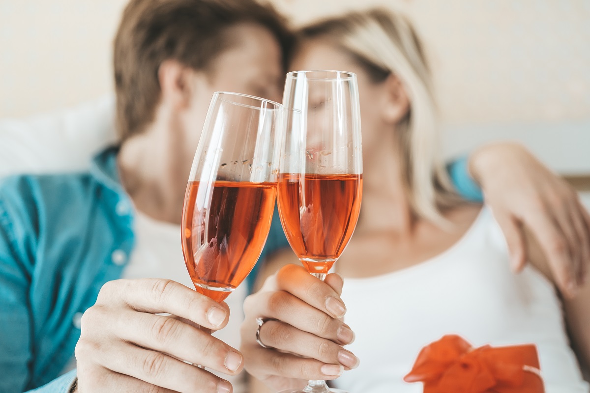 Happy Couple drinking wine in the bedroom