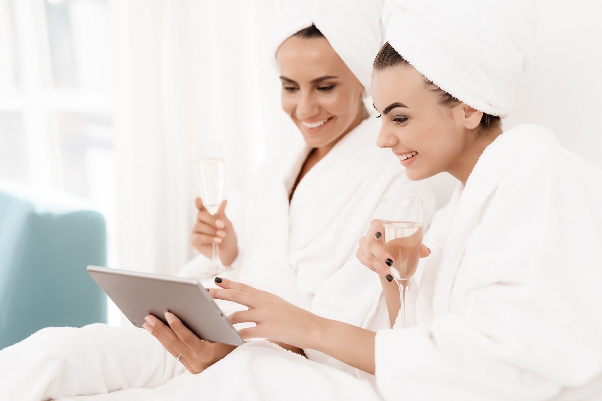 Brunettes in white bathrobes have fun in a bright room.