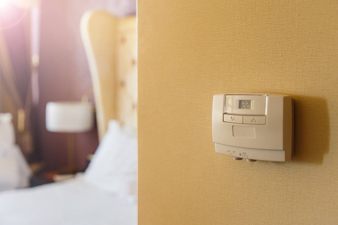 Close-up of a temperature control on a hotel room wall with the room behind it