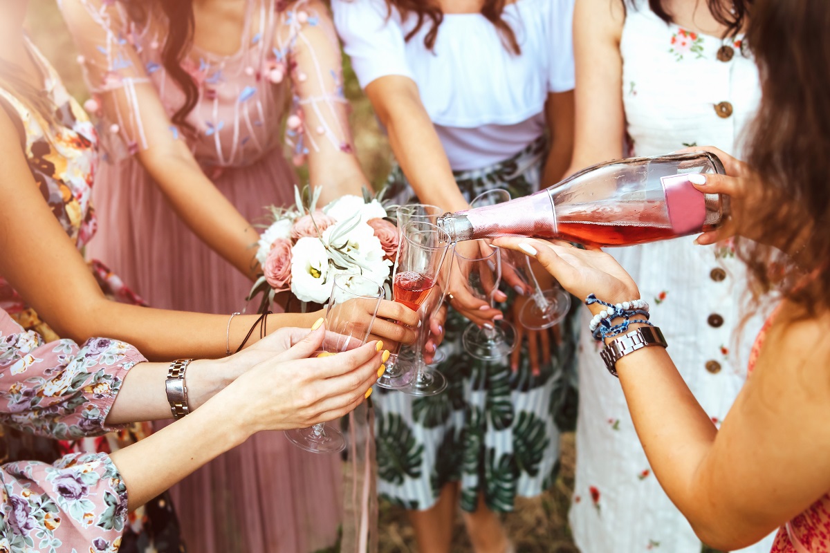 Champagne with glasses in girls hands at hen party outdoor.