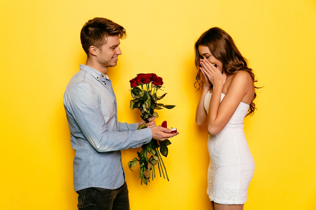 Man with engagement ring and roses making proposition of marriage his girlfriend