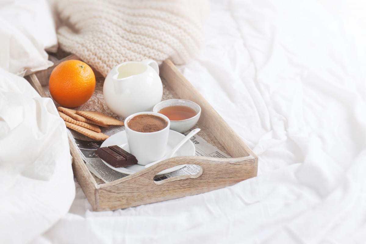 Romantic breakfast on bed with coffee, cookies, orange and choco