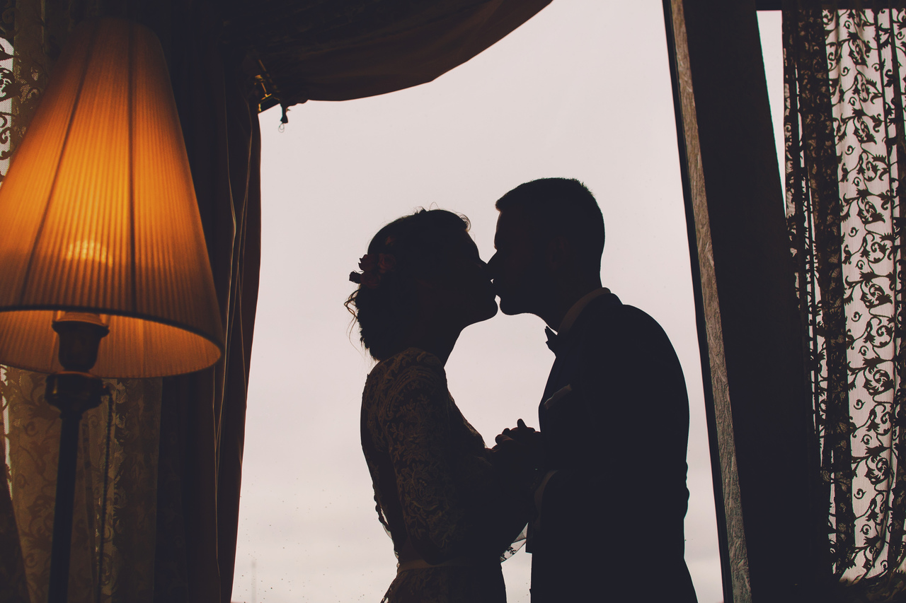 A bride and groom kissing in their hotel suite