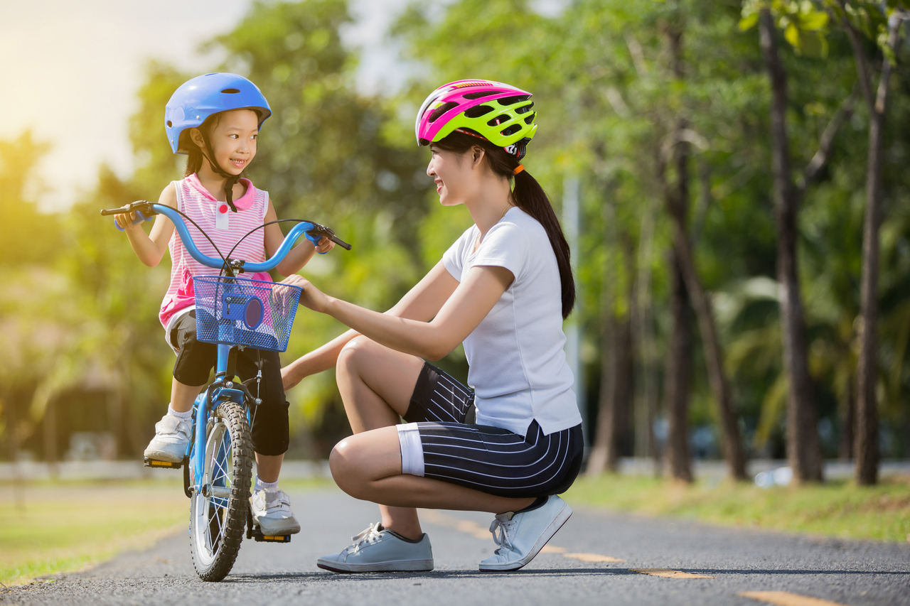 A mother teaching her young daughter how to bike